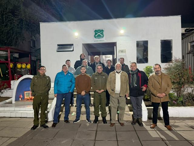 Integrantes del círculo y carabineros posan frente a un cuartel iluminado