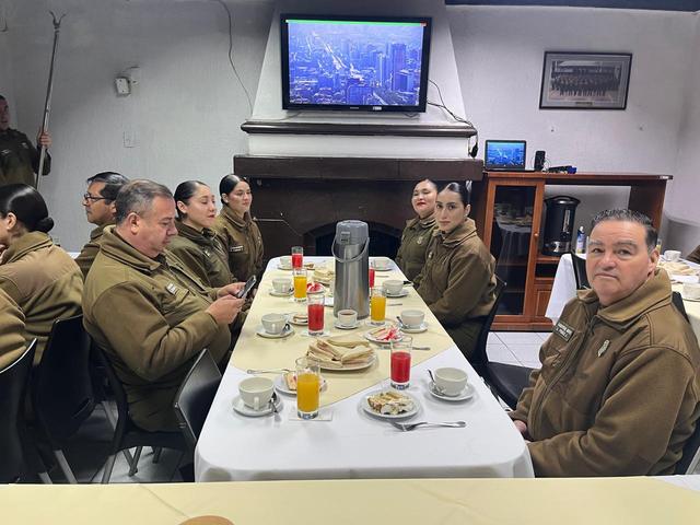 Carabineros conversan en una mesa con mantel blanco